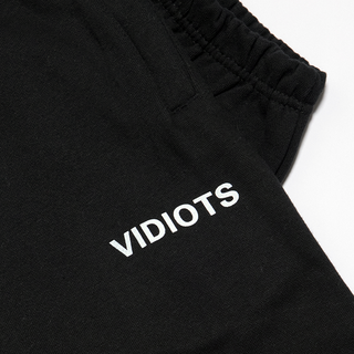 Detail of Black sweatpant with white "Vidiots" text under pocket. 